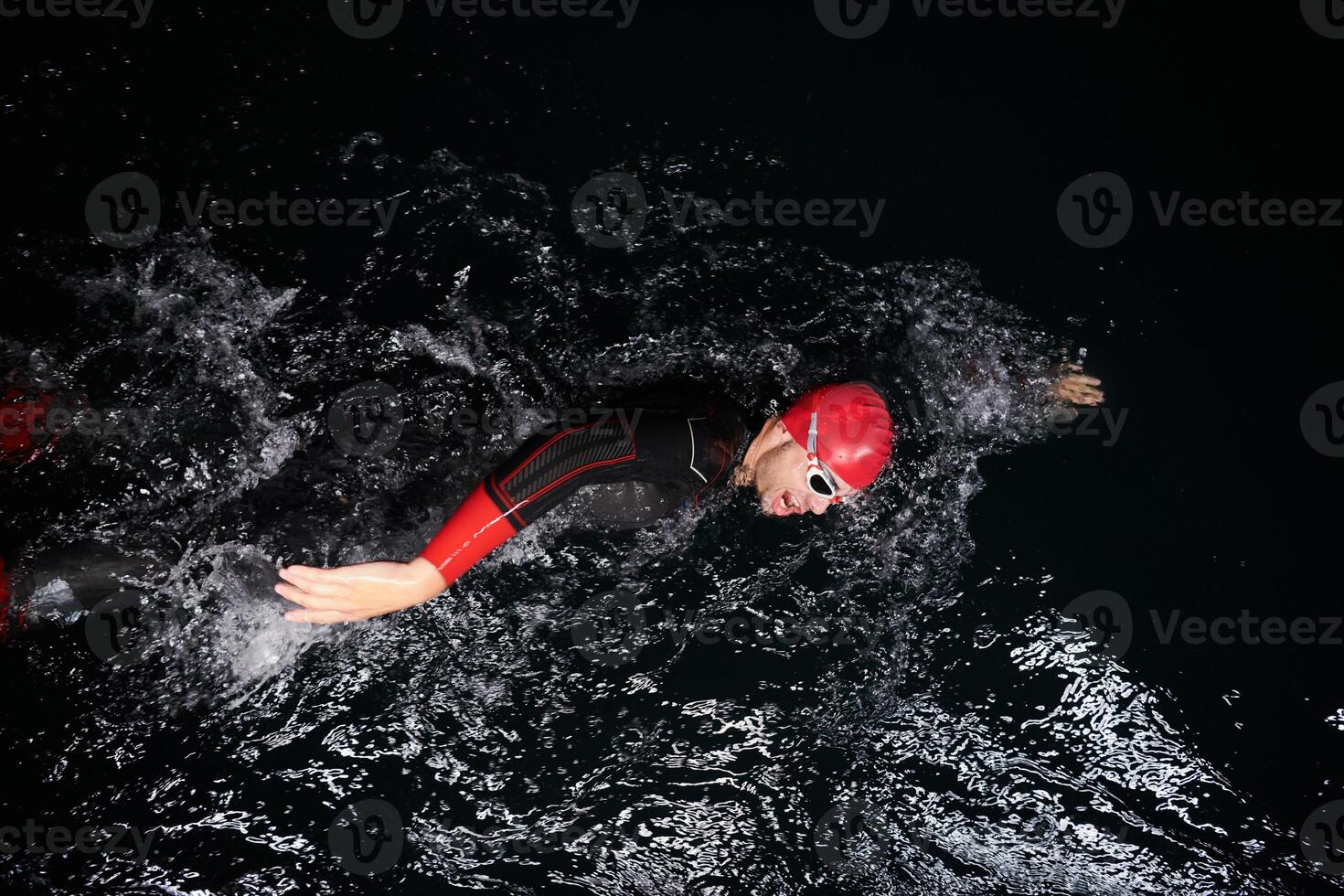 A determined professional triathlete undergoes rigorous night time training in cold waters, showcasing dedication and resilience in preparation for an upcoming triathlon swim competition photo