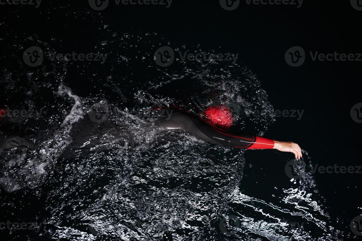A determined professional triathlete undergoes rigorous night time training in cold waters, showcasing dedication and resilience in preparation for an upcoming triathlon swim competition photo