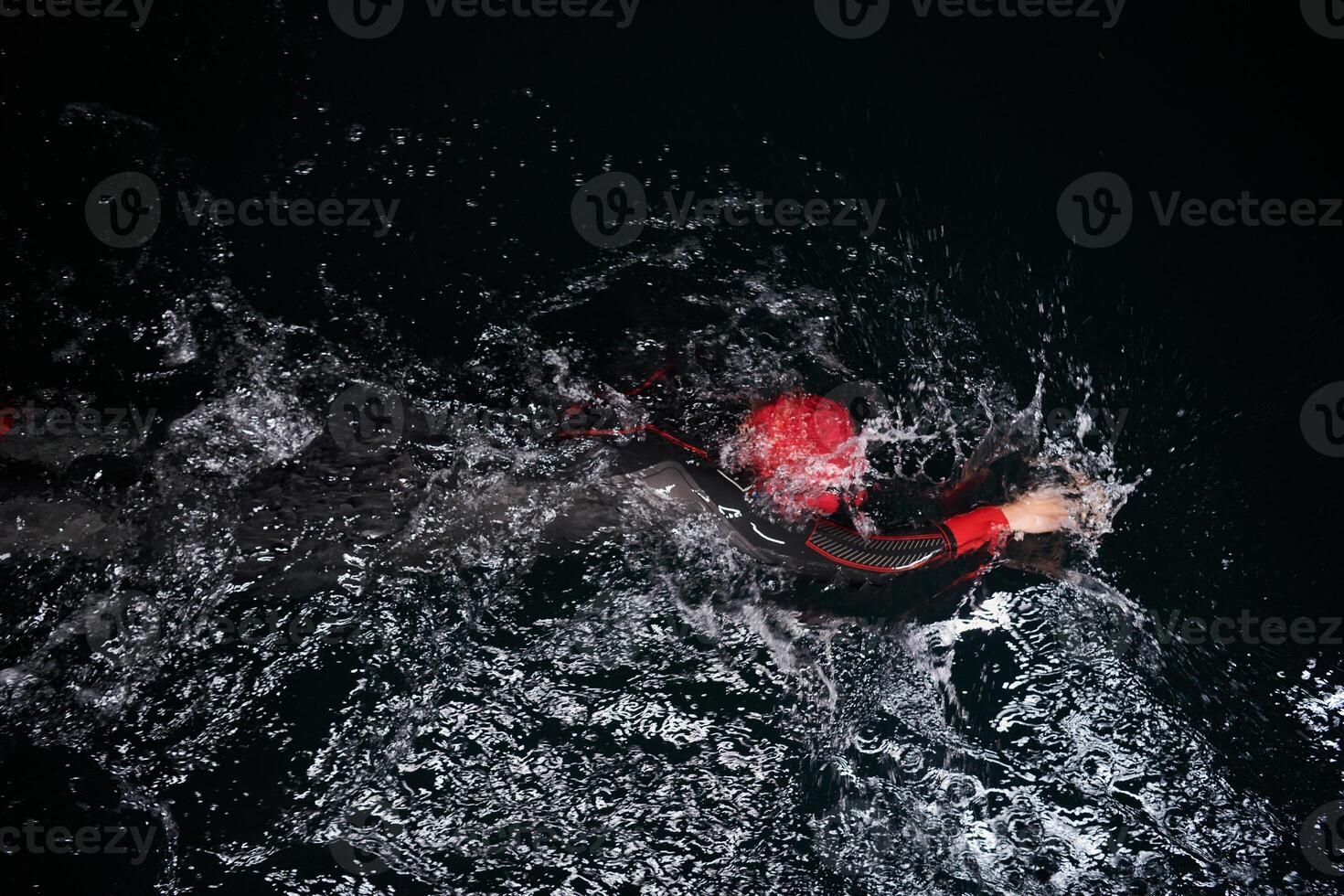 A determined professional triathlete undergoes rigorous night time training in cold waters, showcasing dedication and resilience in preparation for an upcoming triathlon swim competition photo