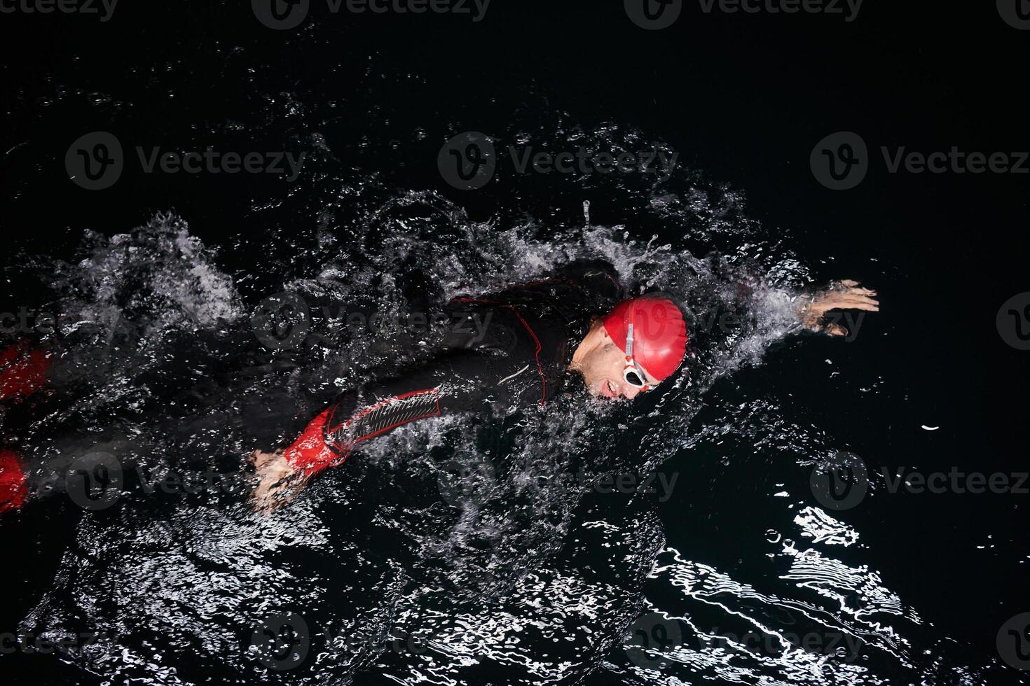 A determined professional triathlete undergoes rigorous night time training in cold waters, showcasing dedication and resilience in preparation for an upcoming triathlon swim competition photo