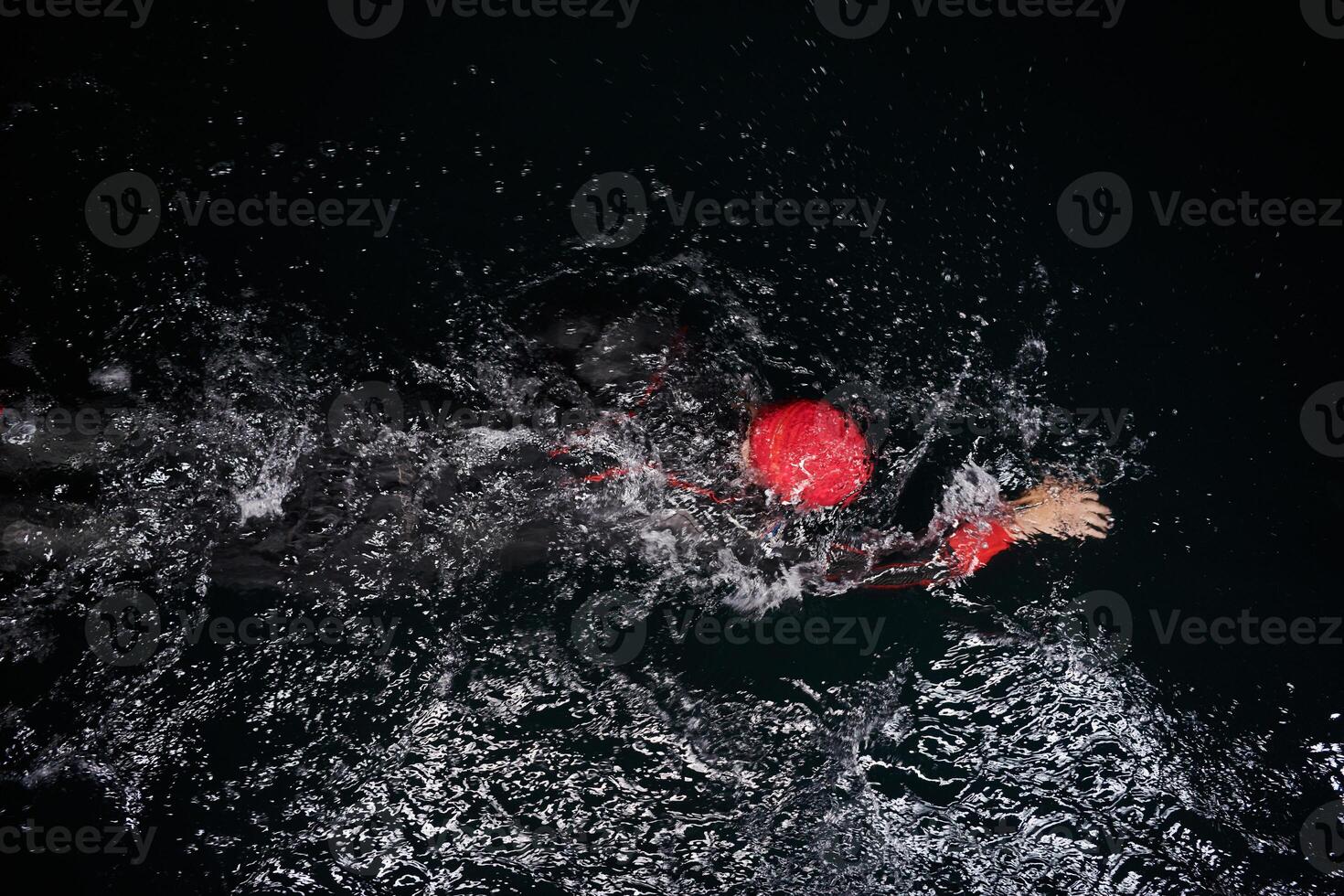 A determined professional triathlete undergoes rigorous night time training in cold waters, showcasing dedication and resilience in preparation for an upcoming triathlon swim competition photo