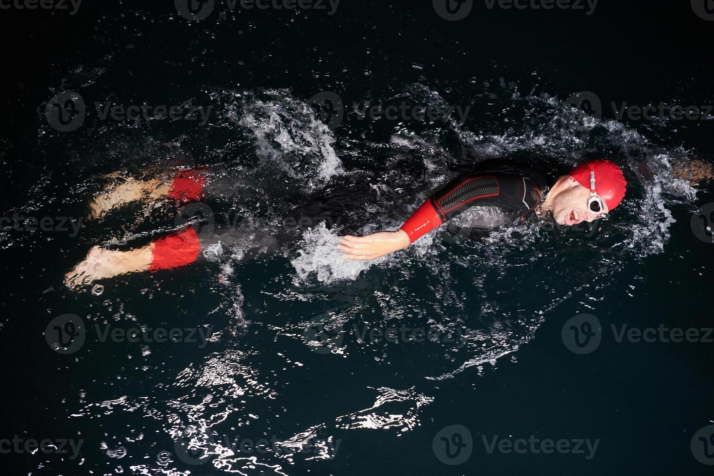 A determined professional triathlete undergoes rigorous night time training in cold waters, showcasing dedication and resilience in preparation for an upcoming triathlon swim competition photo