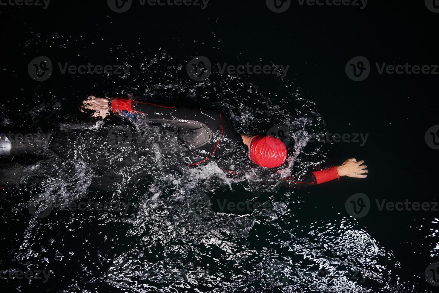 A determined professional triathlete undergoes rigorous night time training in cold waters, showcasing dedication and resilience in preparation for an upcoming triathlon swim competition photo