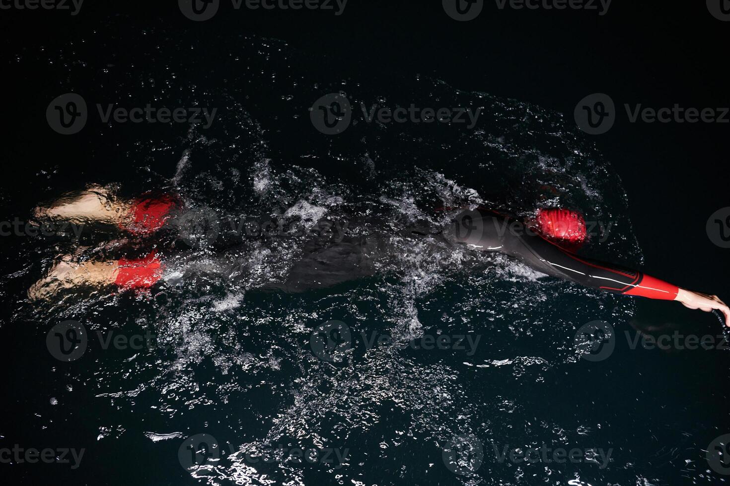 A determined professional triathlete undergoes rigorous night time training in cold waters, showcasing dedication and resilience in preparation for an upcoming triathlon swim competition photo