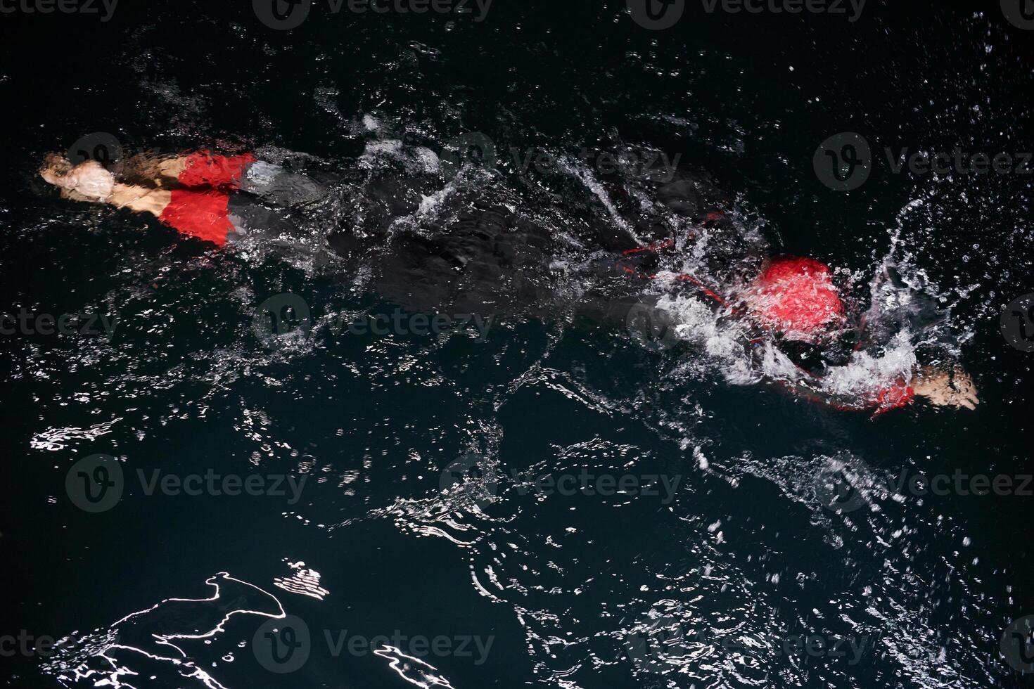 A determined professional triathlete undergoes rigorous night time training in cold waters, showcasing dedication and resilience in preparation for an upcoming triathlon swim competition photo