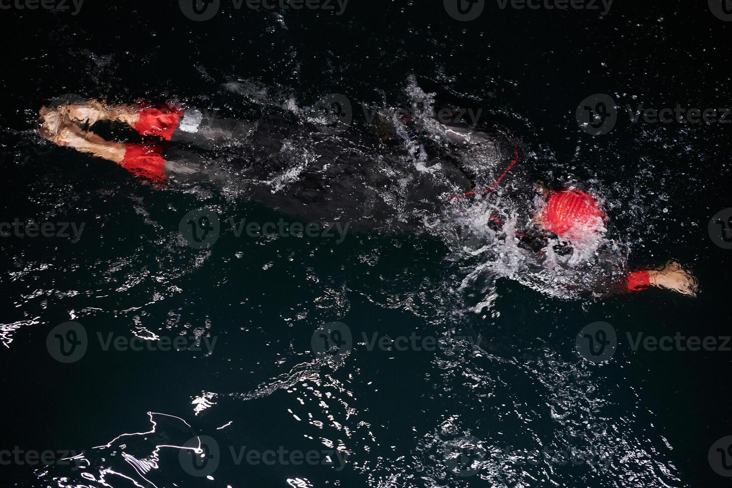 A determined professional triathlete undergoes rigorous night time training in cold waters, showcasing dedication and resilience in preparation for an upcoming triathlon swim competition photo