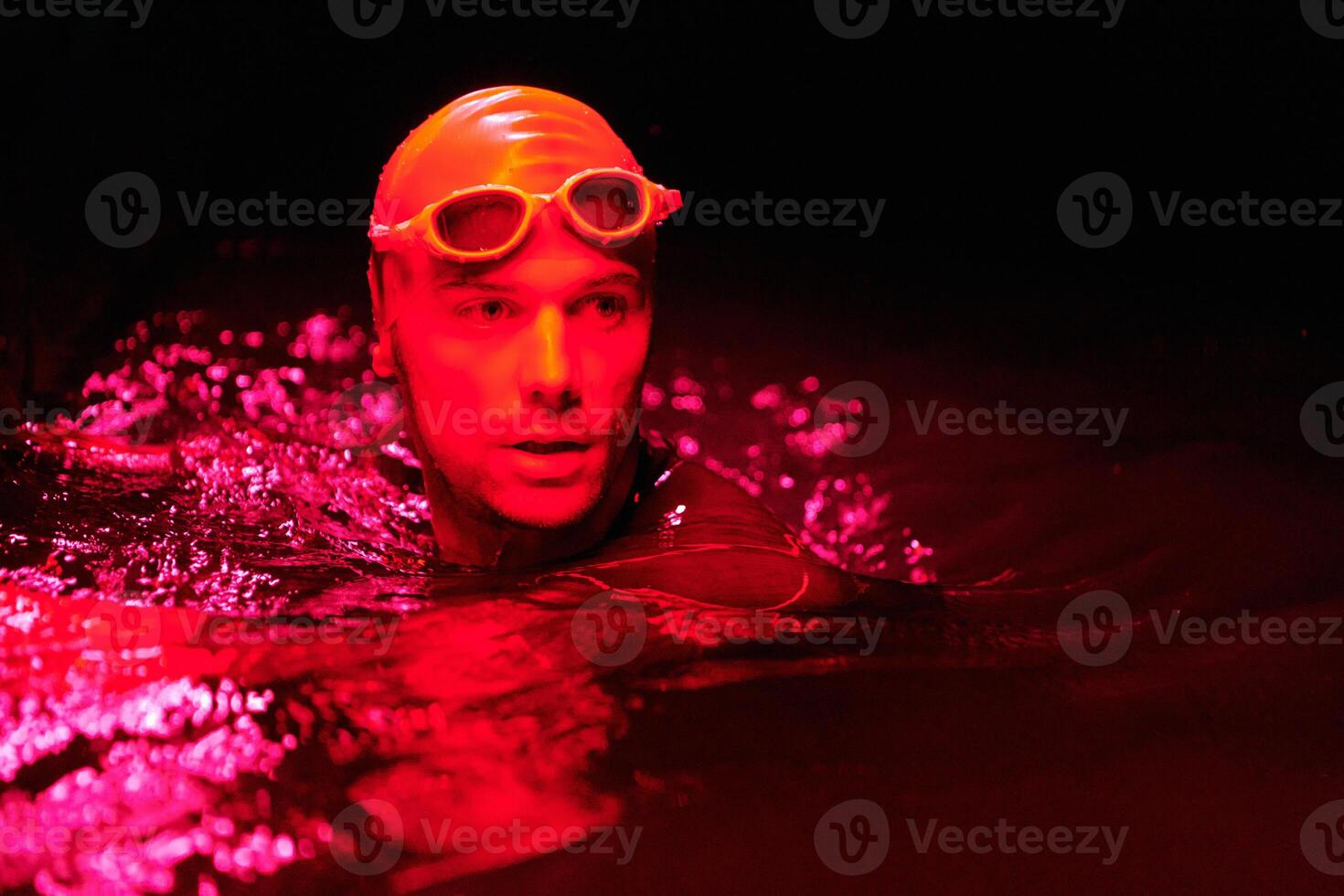 authentic triathlete swimmer having a break during hard training on night neon gel light photo