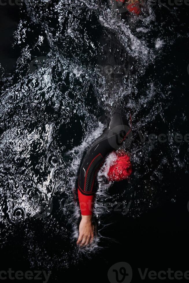 A determined professional triathlete undergoes rigorous night time training in cold waters, showcasing dedication and resilience in preparation for an upcoming triathlon swim competition photo