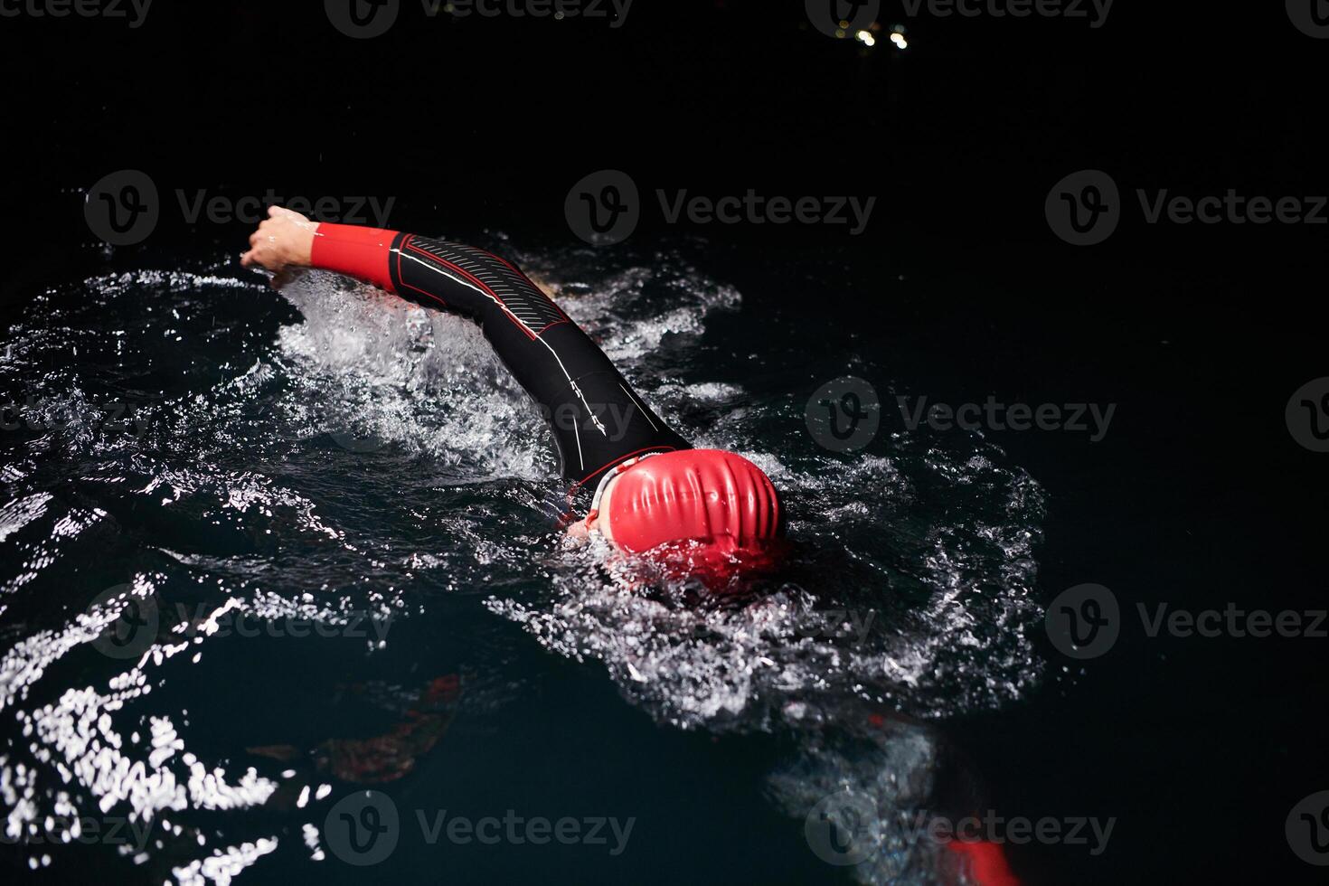 A determined professional triathlete undergoes rigorous night time training in cold waters, showcasing dedication and resilience in preparation for an upcoming triathlon swim competition photo