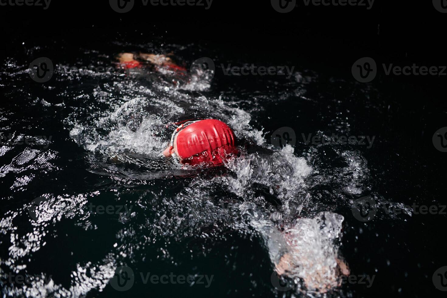 A determined professional triathlete undergoes rigorous night time training in cold waters, showcasing dedication and resilience in preparation for an upcoming triathlon swim competition photo