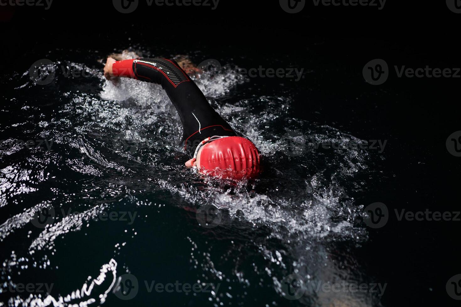 A determined professional triathlete undergoes rigorous night time training in cold waters, showcasing dedication and resilience in preparation for an upcoming triathlon swim competition photo