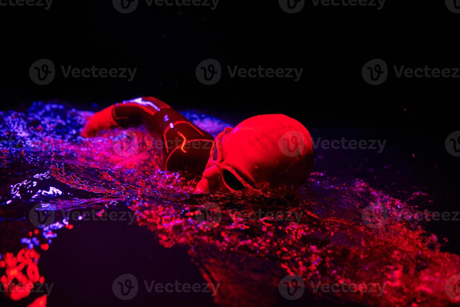 Authentic triathlete swimmer having a break during hard training on night neon gel light photo
