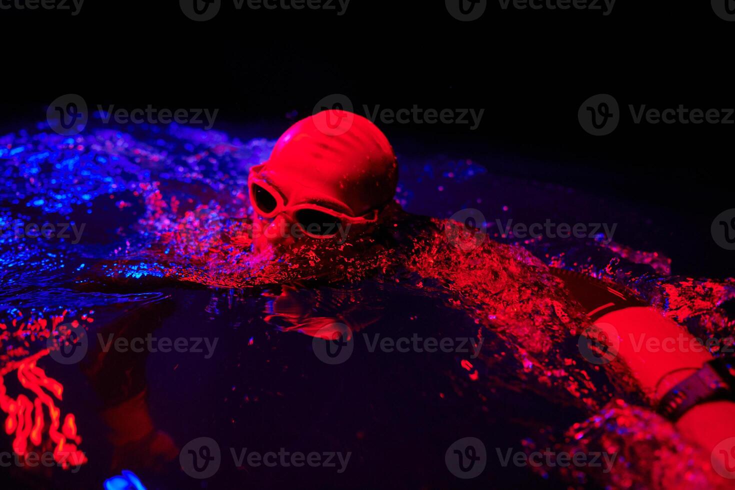 Authentic triathlete swimmer having a break during hard training on night neon gel light photo