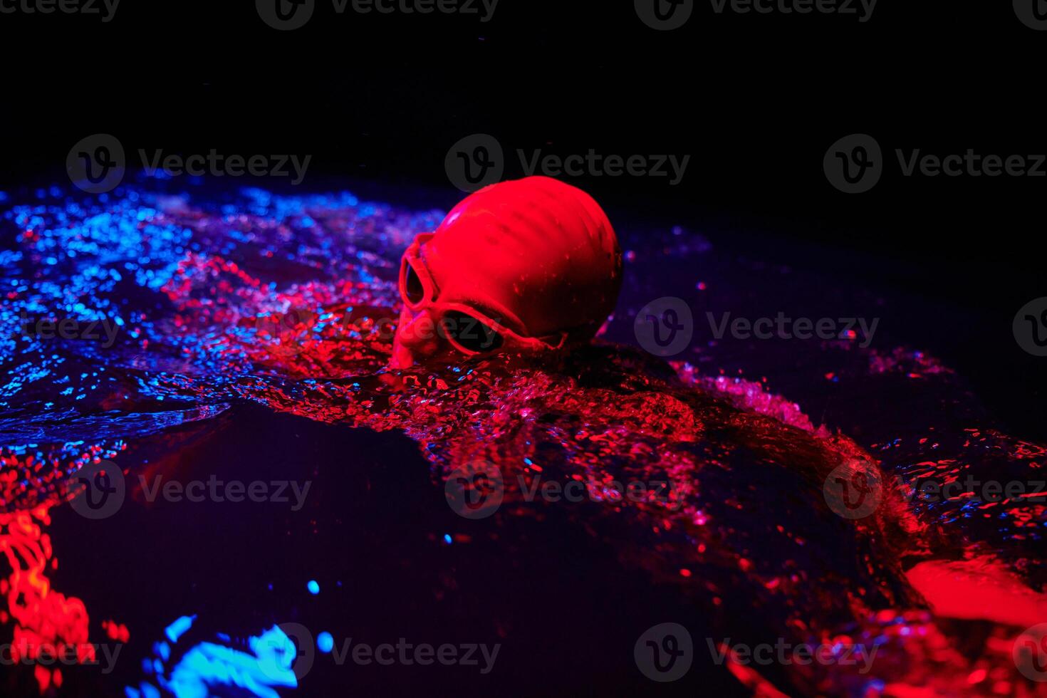 authentic triathlete swimmer having a break during hard training on night neon gel light photo