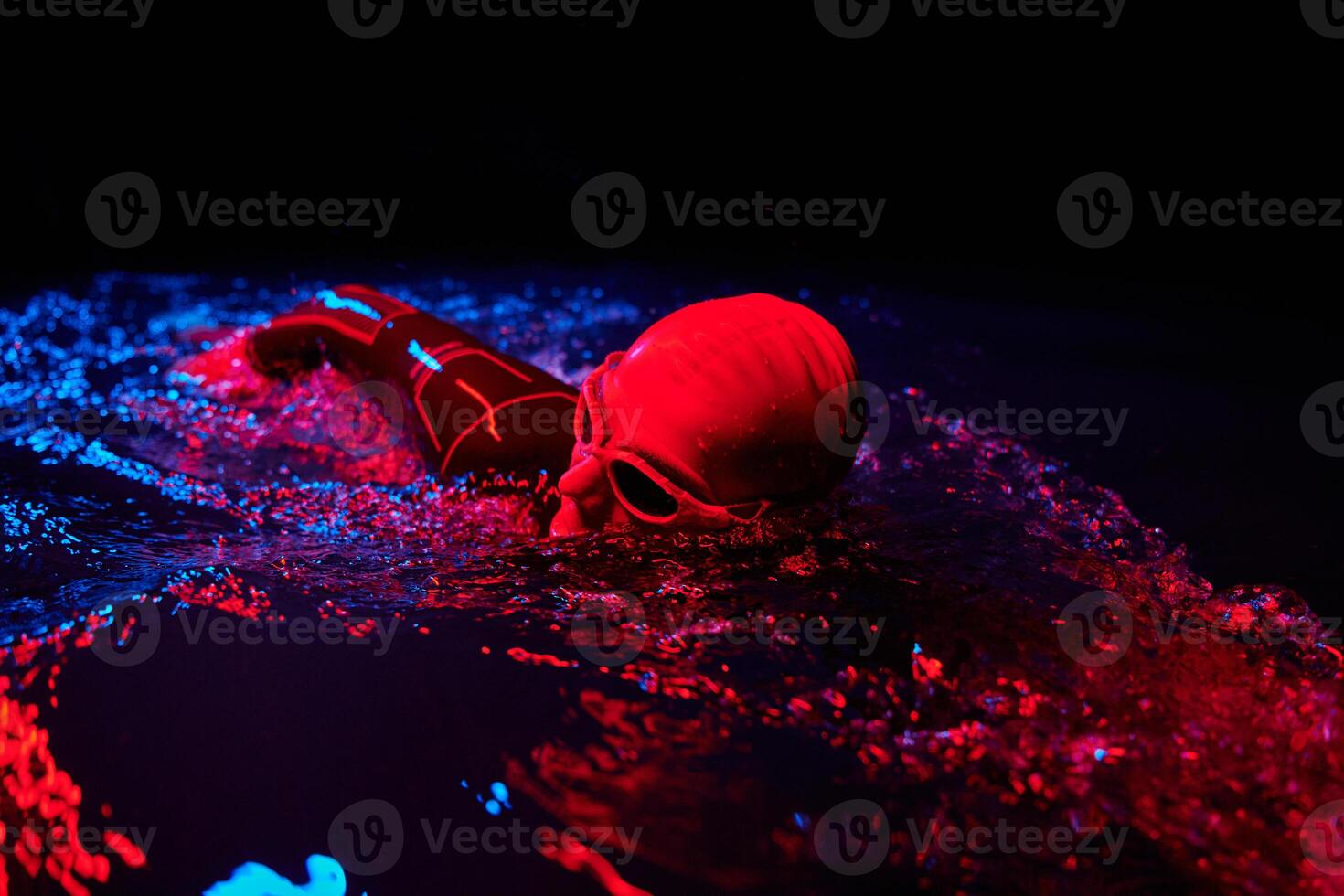 Authentic triathlete swimmer having a break during hard training on night neon gel light photo