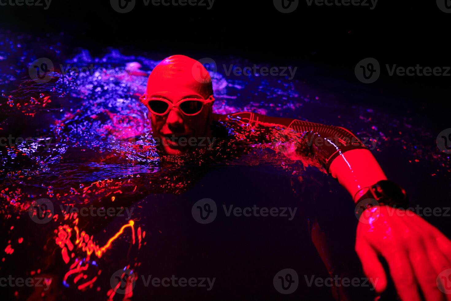 Authentic triathlete swimmer having a break during hard training on night neon gel light photo