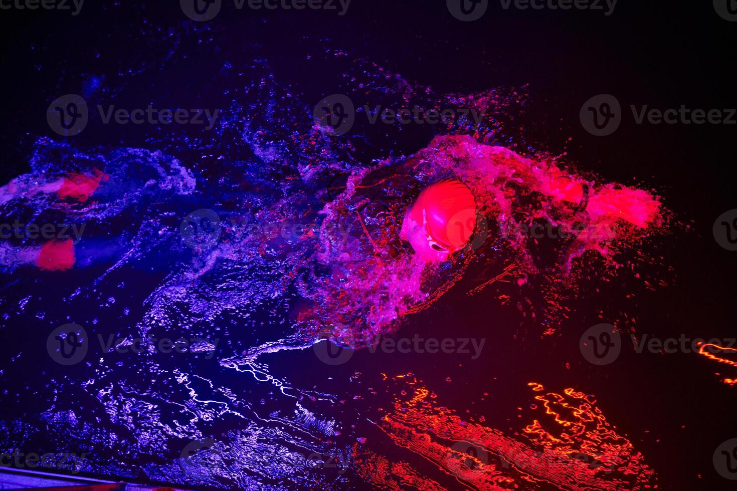 Authentic triathlete swimmer having a break during hard training on night neon gel light photo