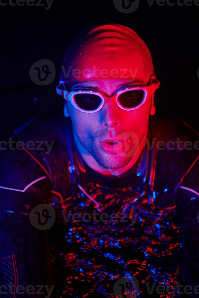 authentic triathlete swimmer having a break during hard training on night neon gel light photo
