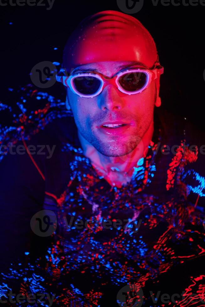 authentic triathlete swimmer having a break during hard training on night neon gel light photo