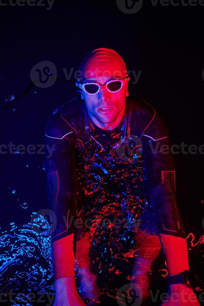 authentic triathlete swimmer having a break during hard training on night neon gel light photo