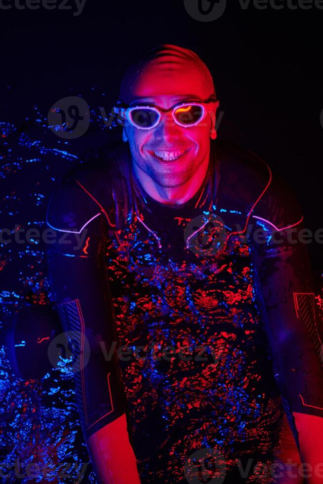 authentic triathlete swimmer having a break during hard training on night neon gel light photo