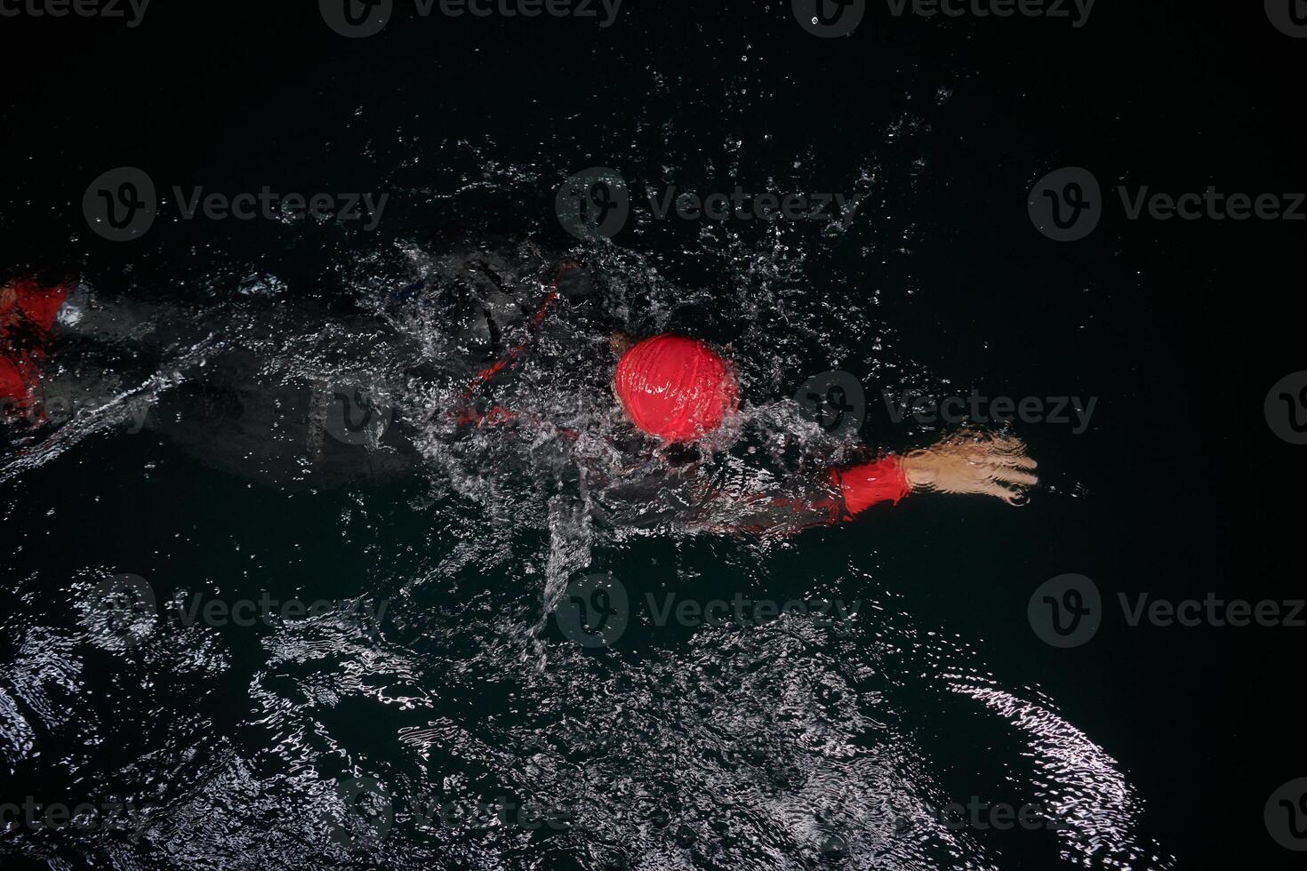 A determined professional triathlete undergoes rigorous night time training in cold waters, showcasing dedication and resilience in preparation for an upcoming triathlon swim competition photo