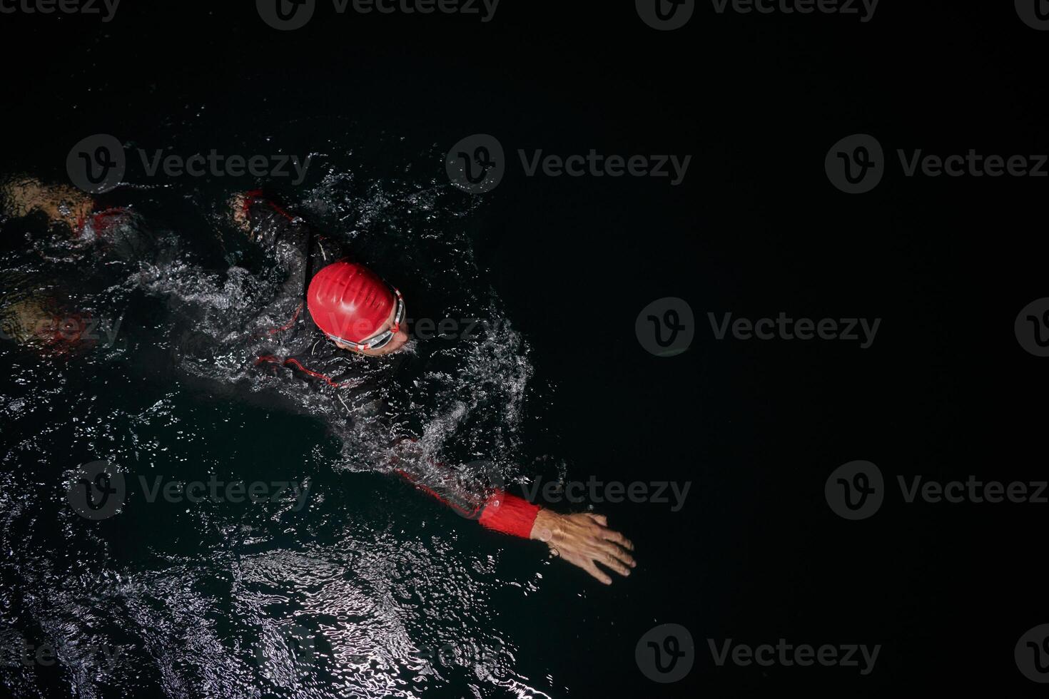 A determined professional triathlete undergoes rigorous night time training in cold waters, showcasing dedication and resilience in preparation for an upcoming triathlon swim competition photo