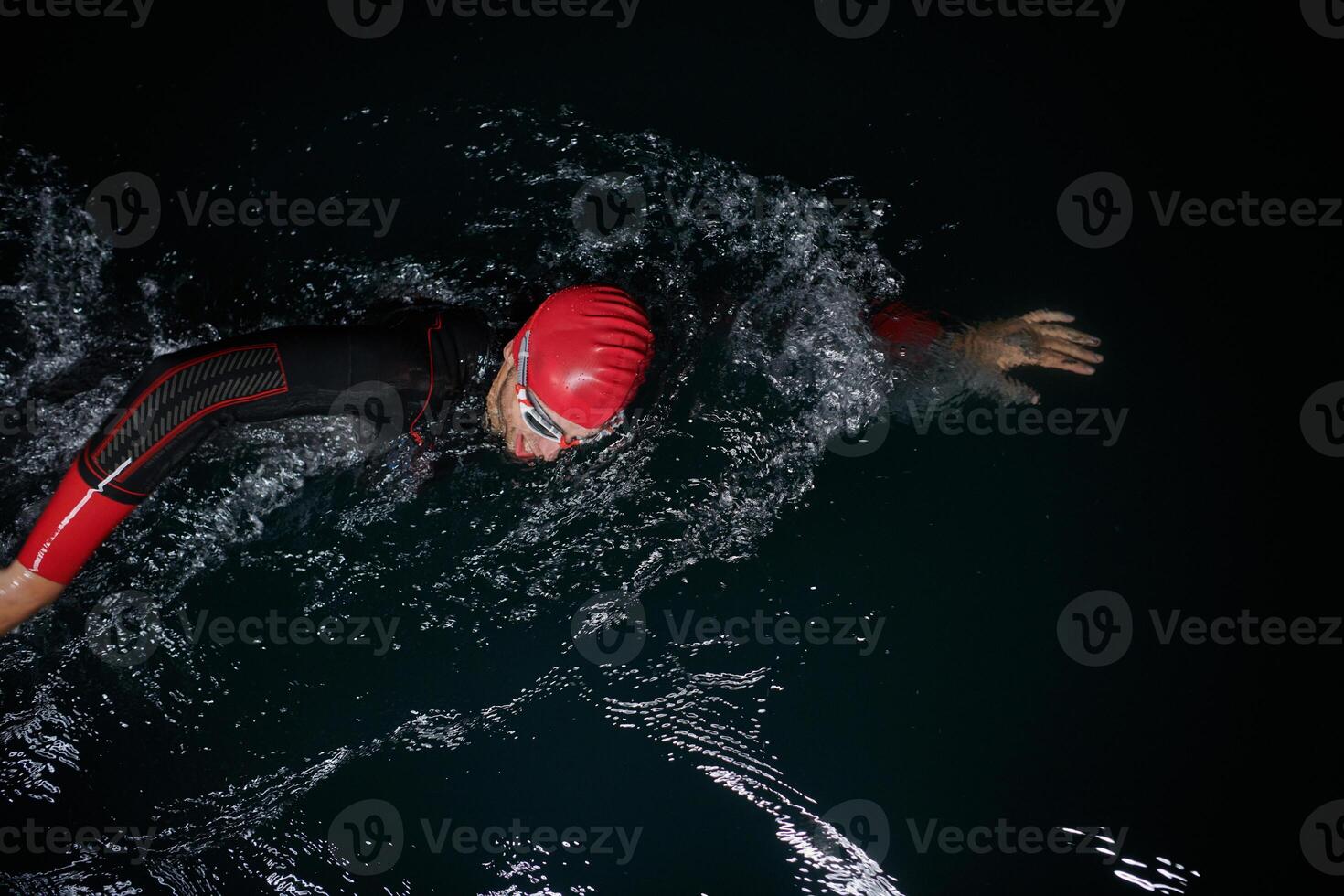A determined professional triathlete undergoes rigorous night time training in cold waters, showcasing dedication and resilience in preparation for an upcoming triathlon swim competition photo