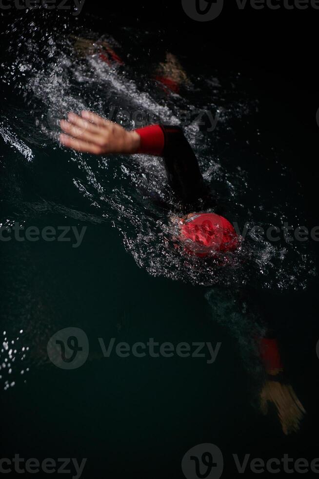 A determined professional triathlete undergoes rigorous night time training in cold waters, showcasing dedication and resilience in preparation for an upcoming triathlon swim competition photo
