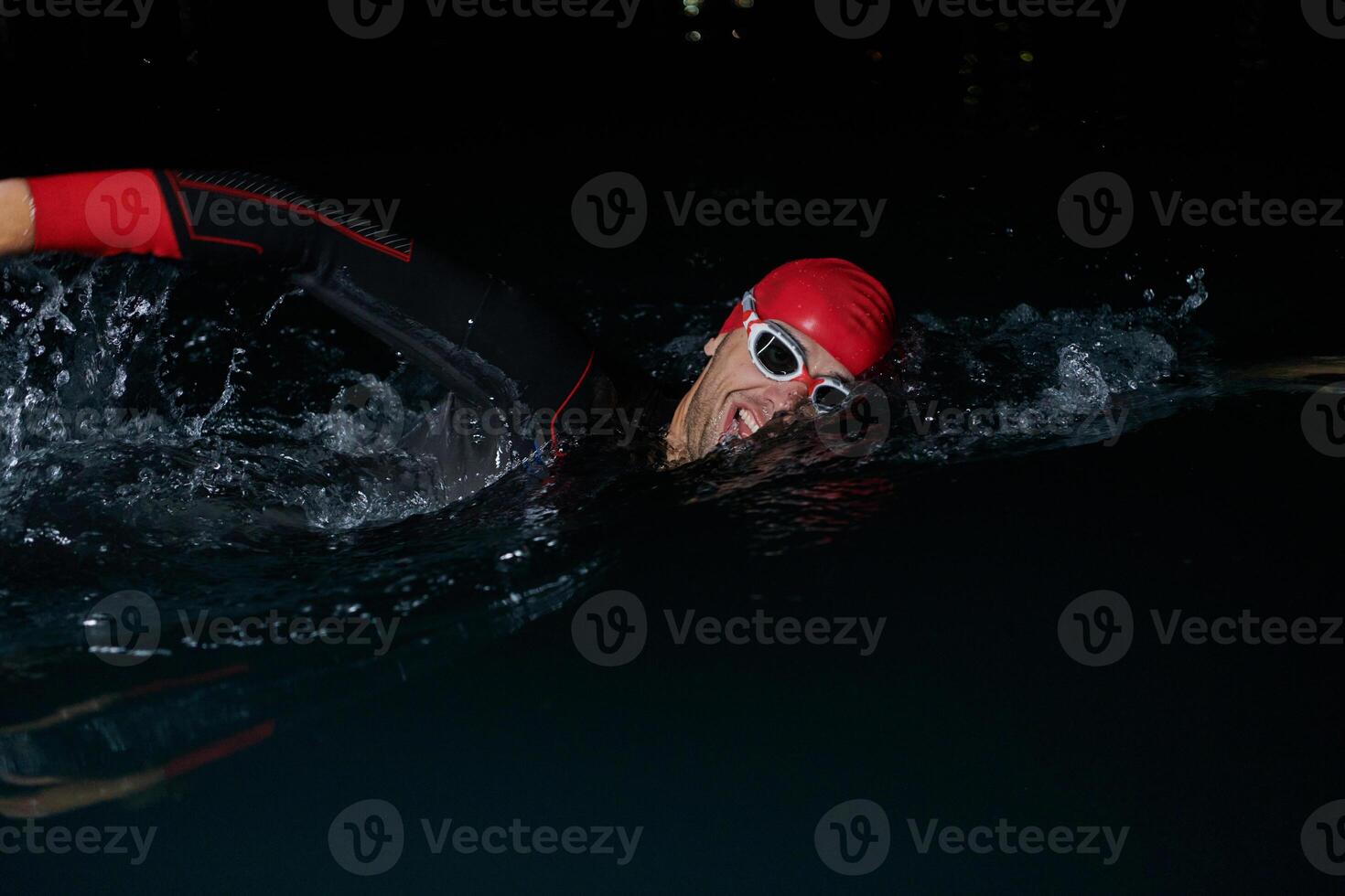 A determined professional triathlete undergoes rigorous night time training in cold waters, showcasing dedication and resilience in preparation for an upcoming triathlon swim competition photo