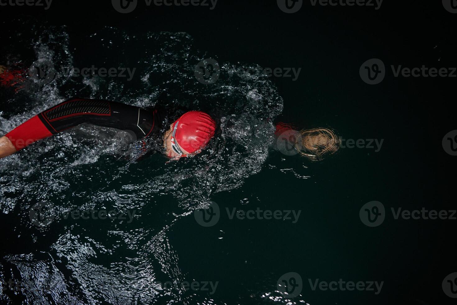 A determined professional triathlete undergoes rigorous night time training in cold waters, showcasing dedication and resilience in preparation for an upcoming triathlon swim competition photo