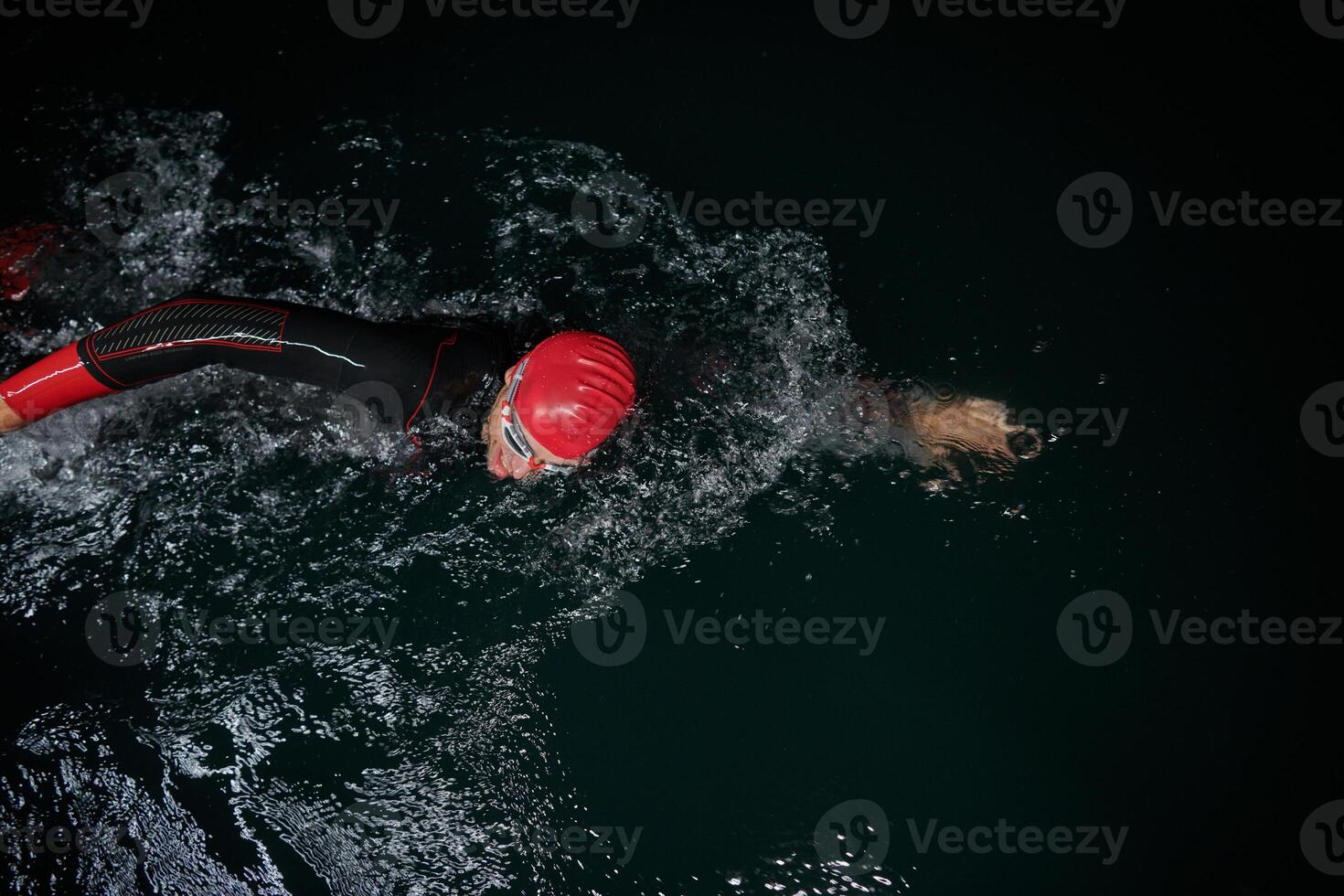A determined professional triathlete undergoes rigorous night time training in cold waters, showcasing dedication and resilience in preparation for an upcoming triathlon swim competition photo