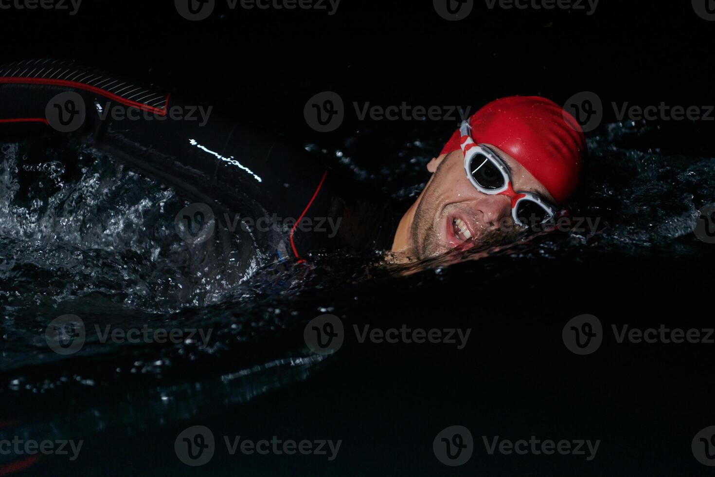 A determined professional triathlete undergoes rigorous night time training in cold waters, showcasing dedication and resilience in preparation for an upcoming triathlon swim competition photo