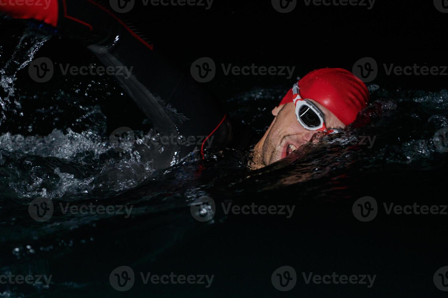 A determined professional triathlete undergoes rigorous night time training in cold waters, showcasing dedication and resilience in preparation for an upcoming triathlon swim competition photo