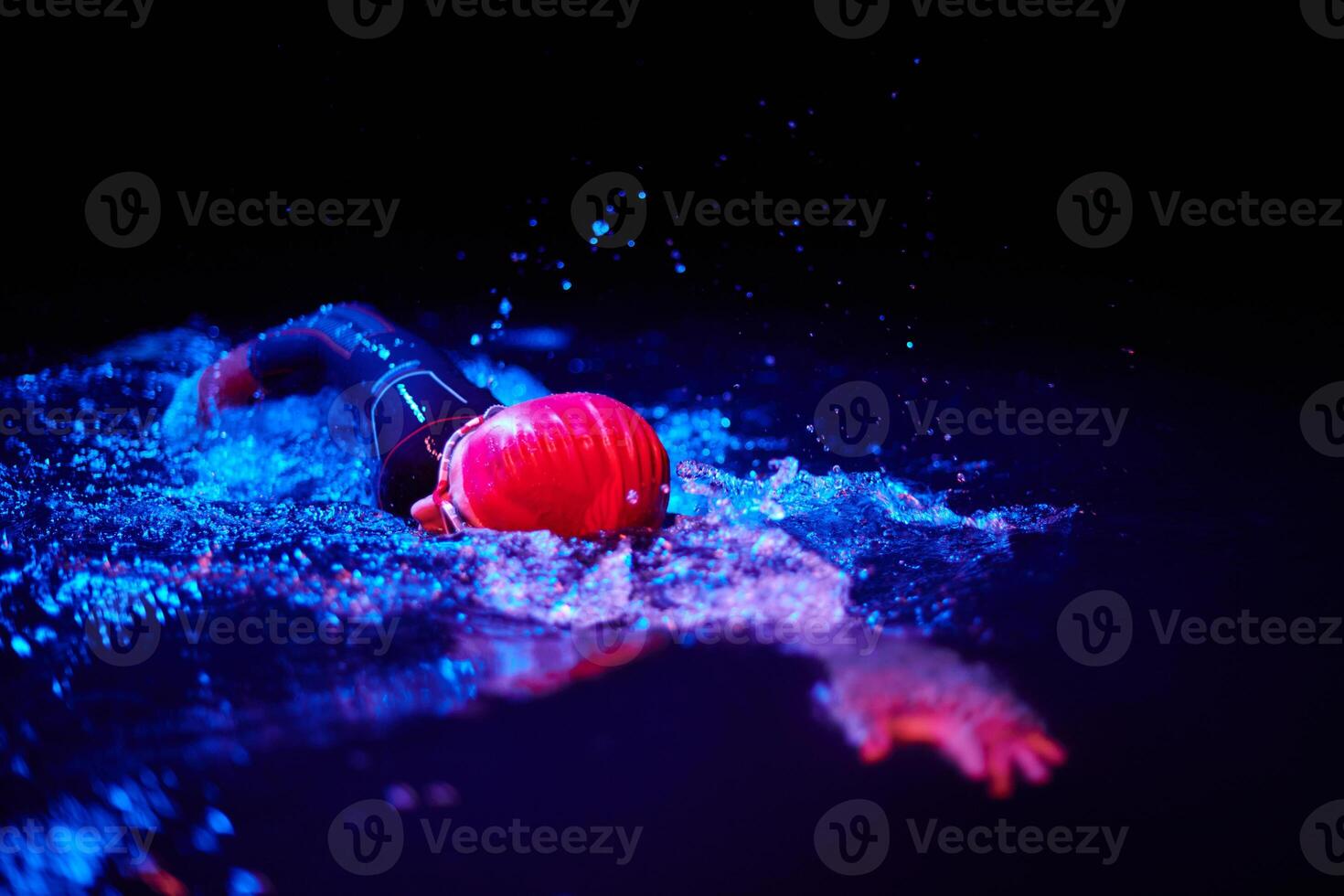 Authentic triathlete swimmer having a break during hard training on night neon gel light photo
