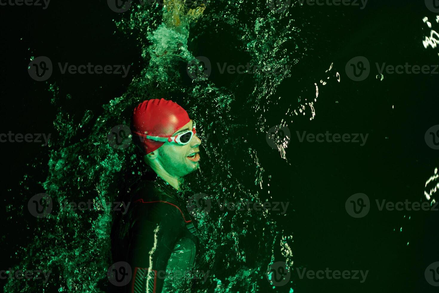 Authentic triathlete swimmer having a break during hard training on night neon gel light photo