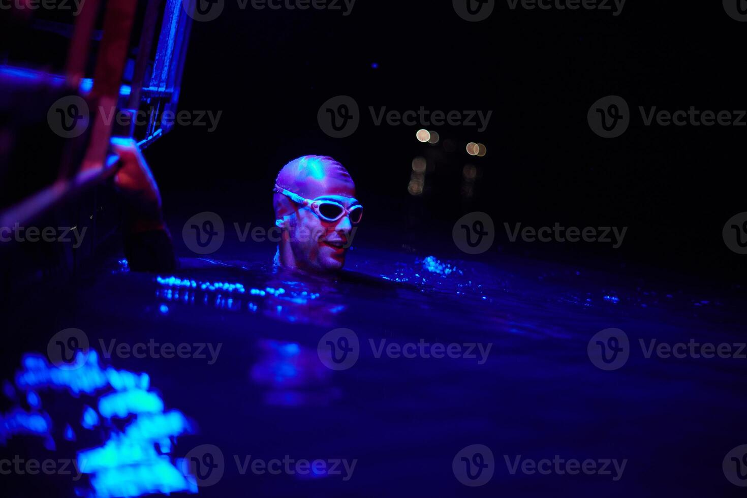 authentic triathlete swimmer having a break during hard training on night neon gel light photo