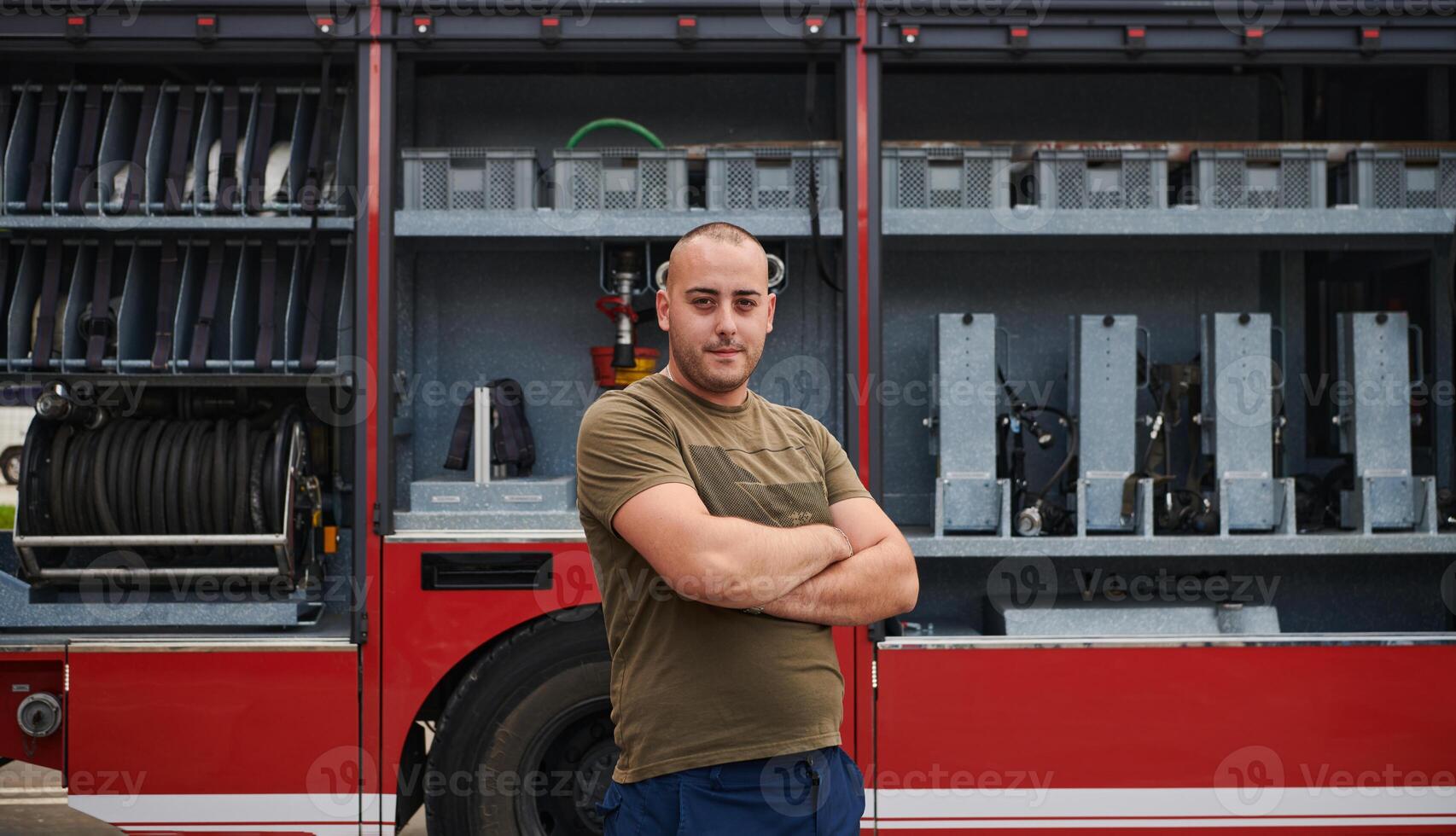 Confident firefighter stands with crossed arms, exuding resilience and preparedness, ready to respond to emergencies alongside a modern fire truck, showcasing the heroism and strength of the fire photo