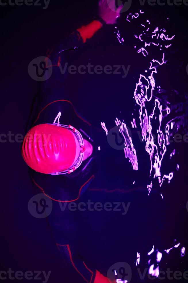 Authentic triathlete swimmer having a break during hard training on night neon gel light photo