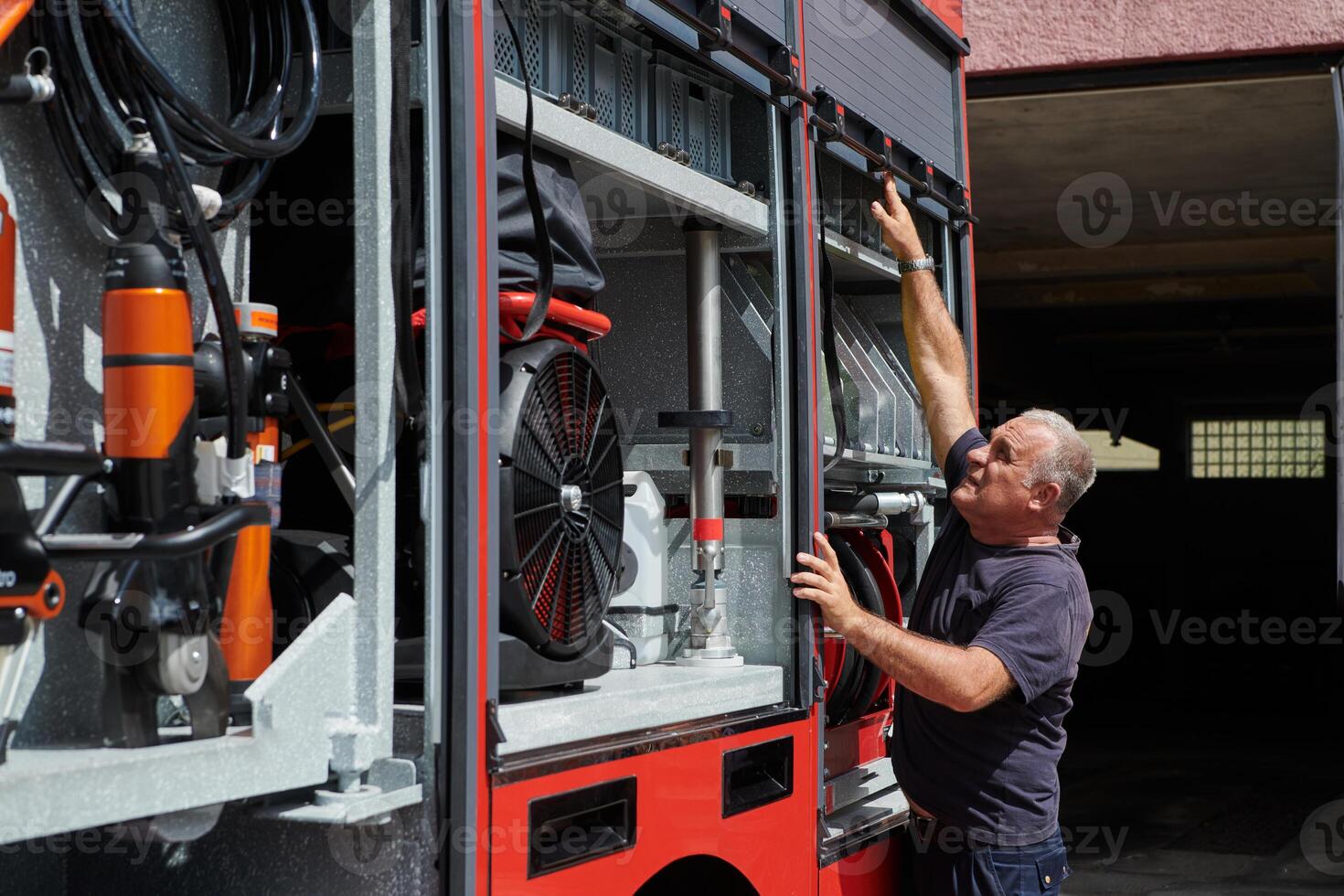 A dedicated firefighter preparing a modern firetruck for deployment to hazardous fire-stricken areas, demonstrating readiness and commitment to emergency response photo