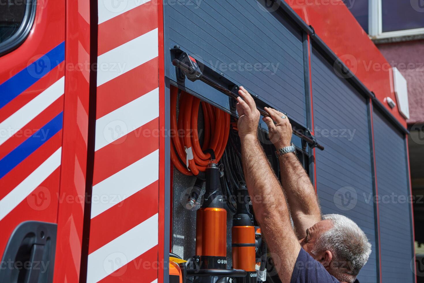 A dedicated firefighter preparing a modern firetruck for deployment to hazardous fire-stricken areas, demonstrating readiness and commitment to emergency response photo