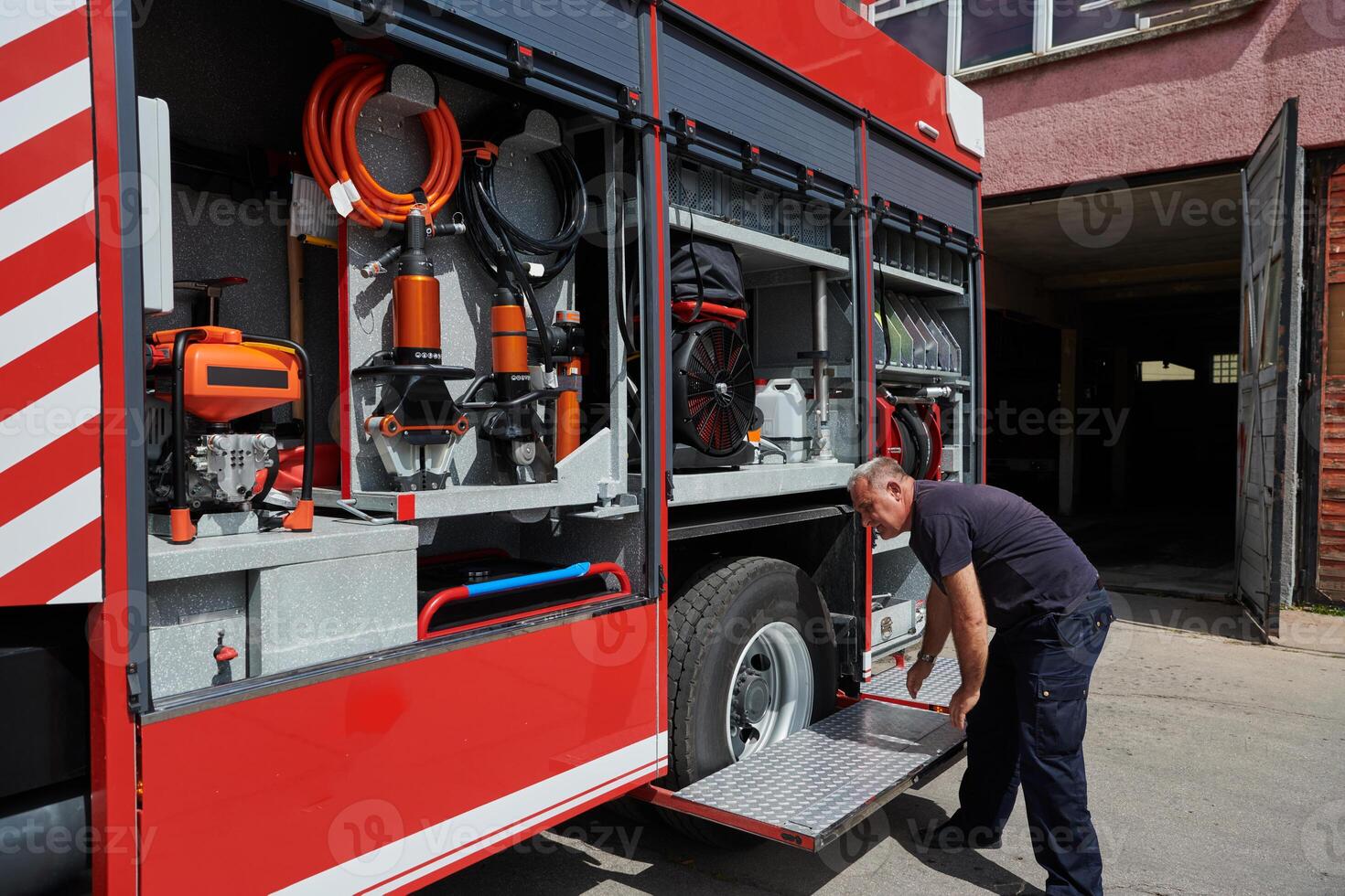 A dedicated firefighter preparing a modern firetruck for deployment to hazardous fire-stricken areas, demonstrating readiness and commitment to emergency response photo