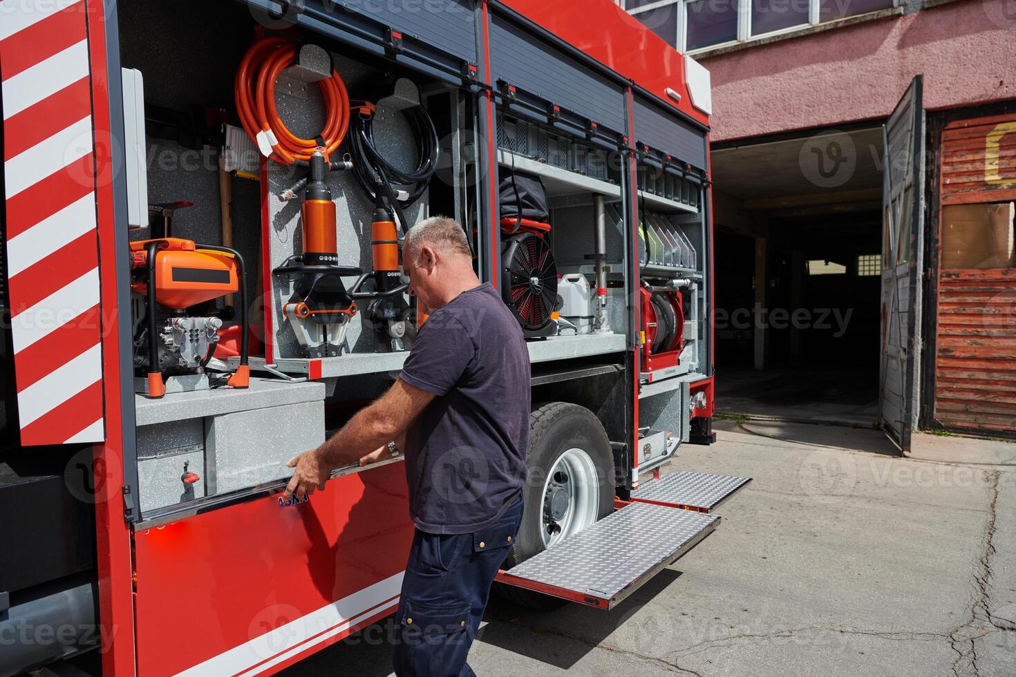 A dedicated firefighter preparing a modern firetruck for deployment to hazardous fire-stricken areas, demonstrating readiness and commitment to emergency response photo