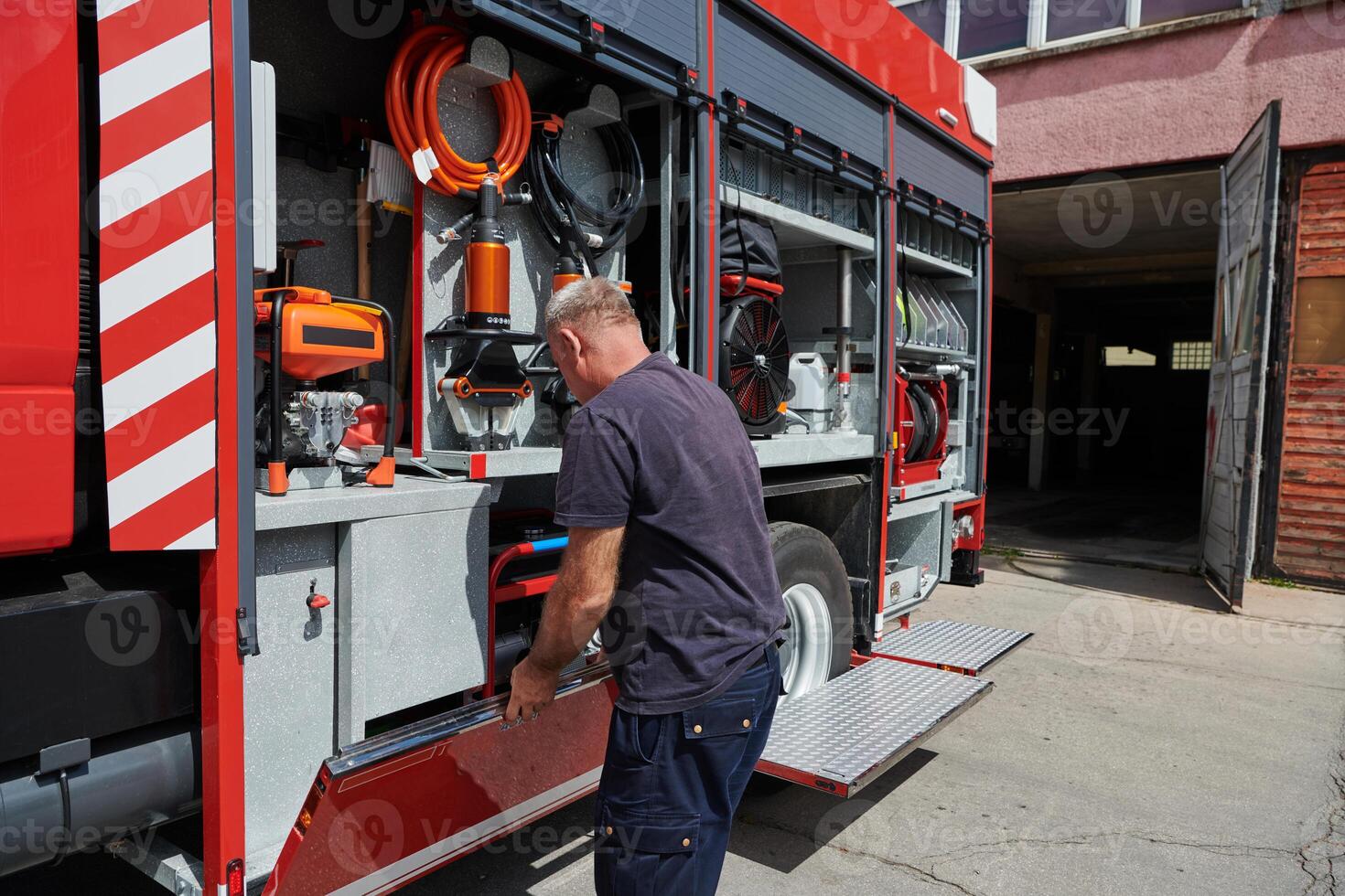 A dedicated firefighter preparing a modern firetruck for deployment to hazardous fire-stricken areas, demonstrating readiness and commitment to emergency response photo