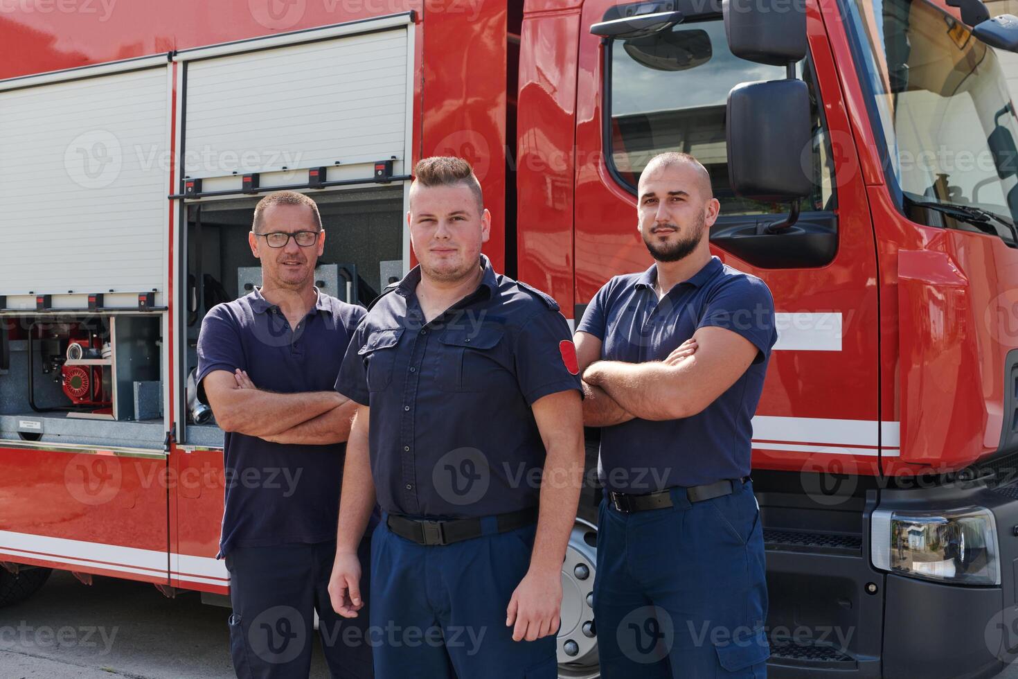 A skilled and dedicated professional firefighting team proudly poses in front of their state of the art firetruck, showcasing their modern equipment and commitment to ensuring public safety. photo