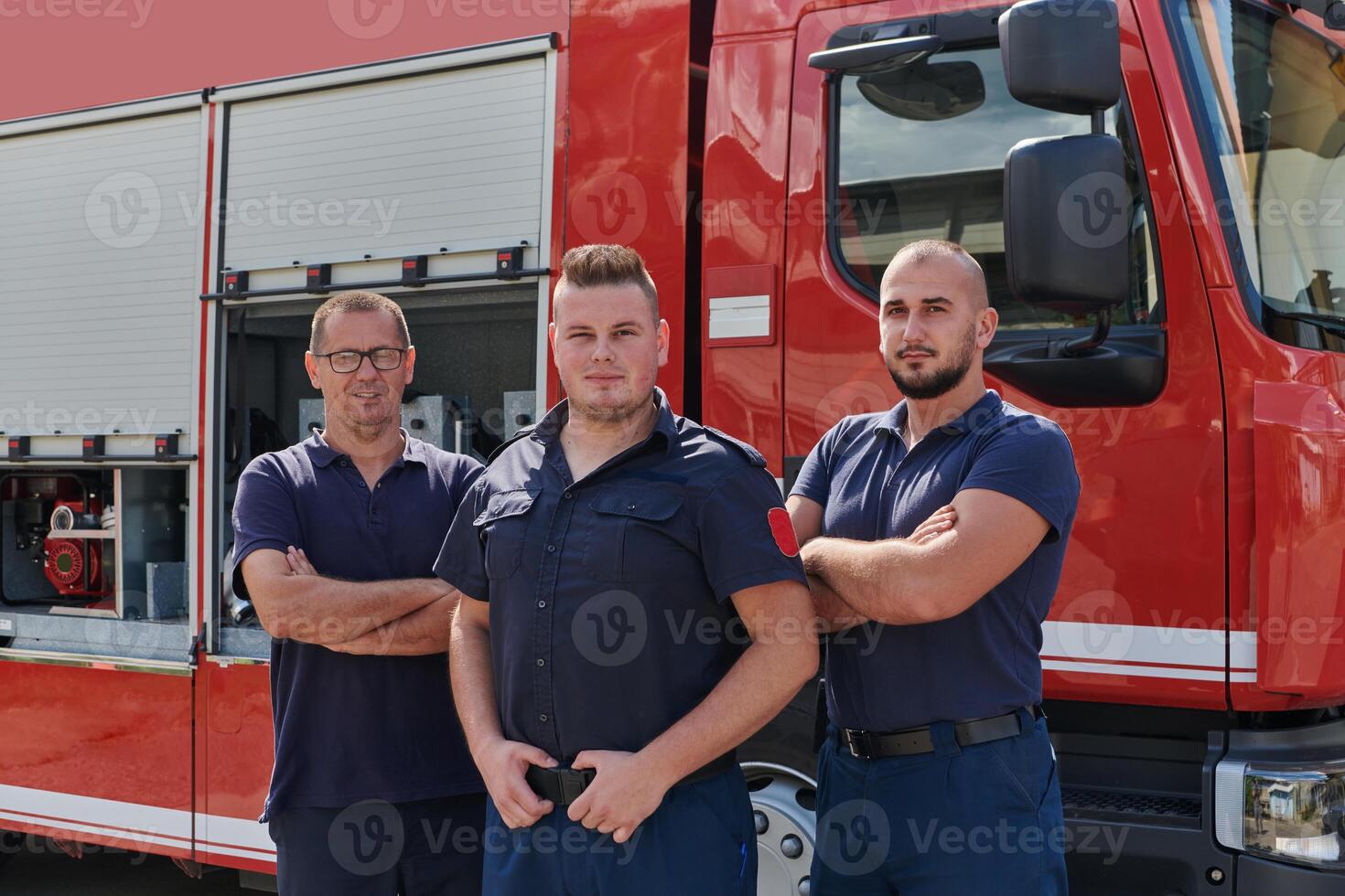 A skilled and dedicated professional firefighting team proudly poses in front of their state of the art firetruck, showcasing their modern equipment and commitment to ensuring public safety. photo