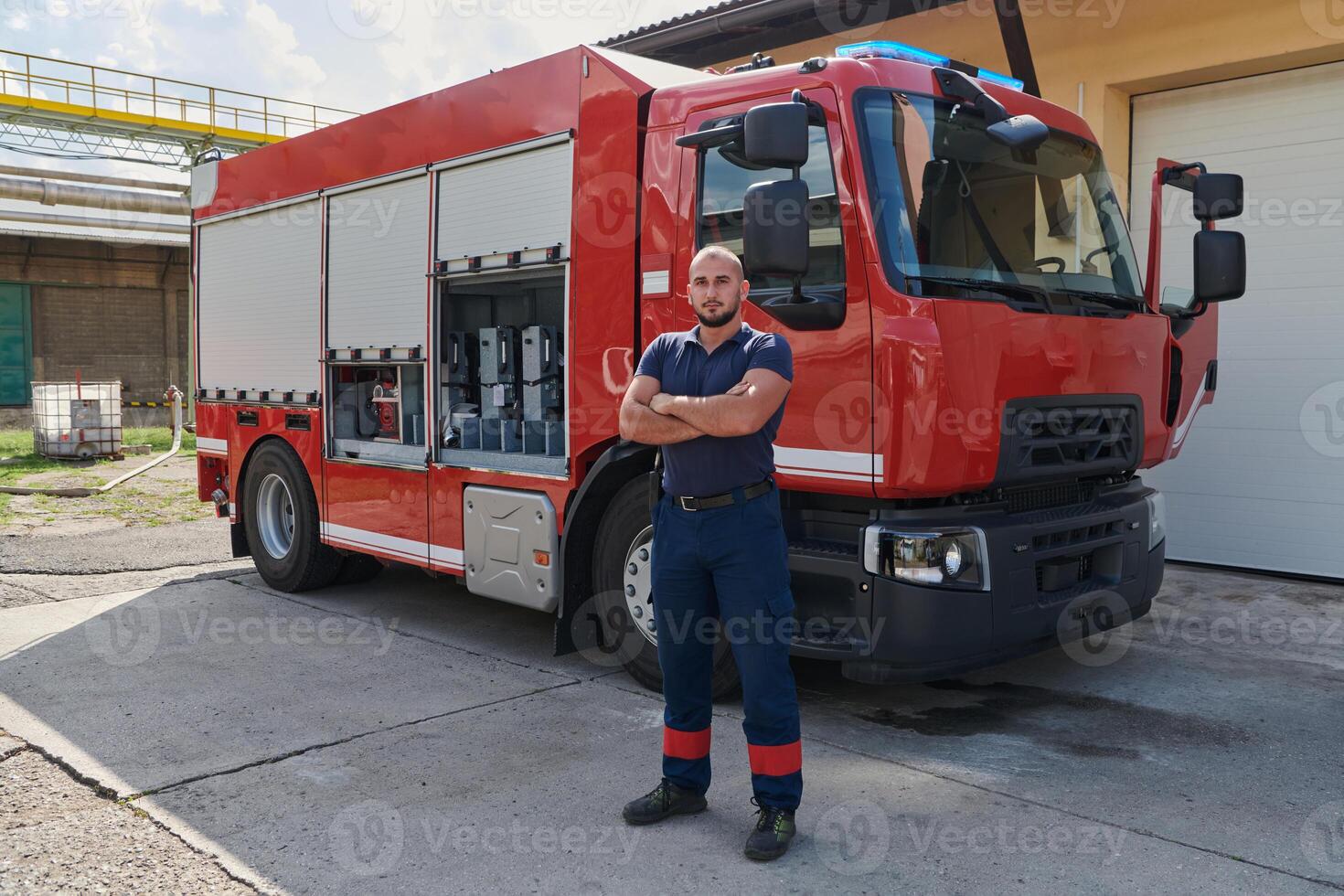 Confident firefighter stands with crossed arms, exuding resilience and preparedness, ready to respond to emergencies alongside a modern fire truck, showcasing the heroism and strength of the fire photo