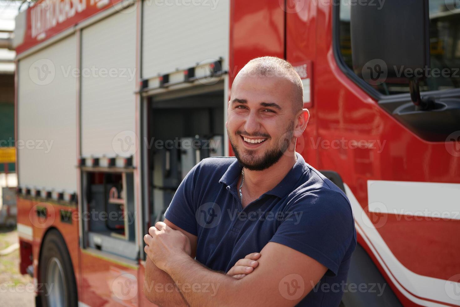 Confident firefighter stands with crossed arms, exuding resilience and preparedness, ready to respond to emergencies alongside a modern fire truck, showcasing the heroism and strength of the fire photo