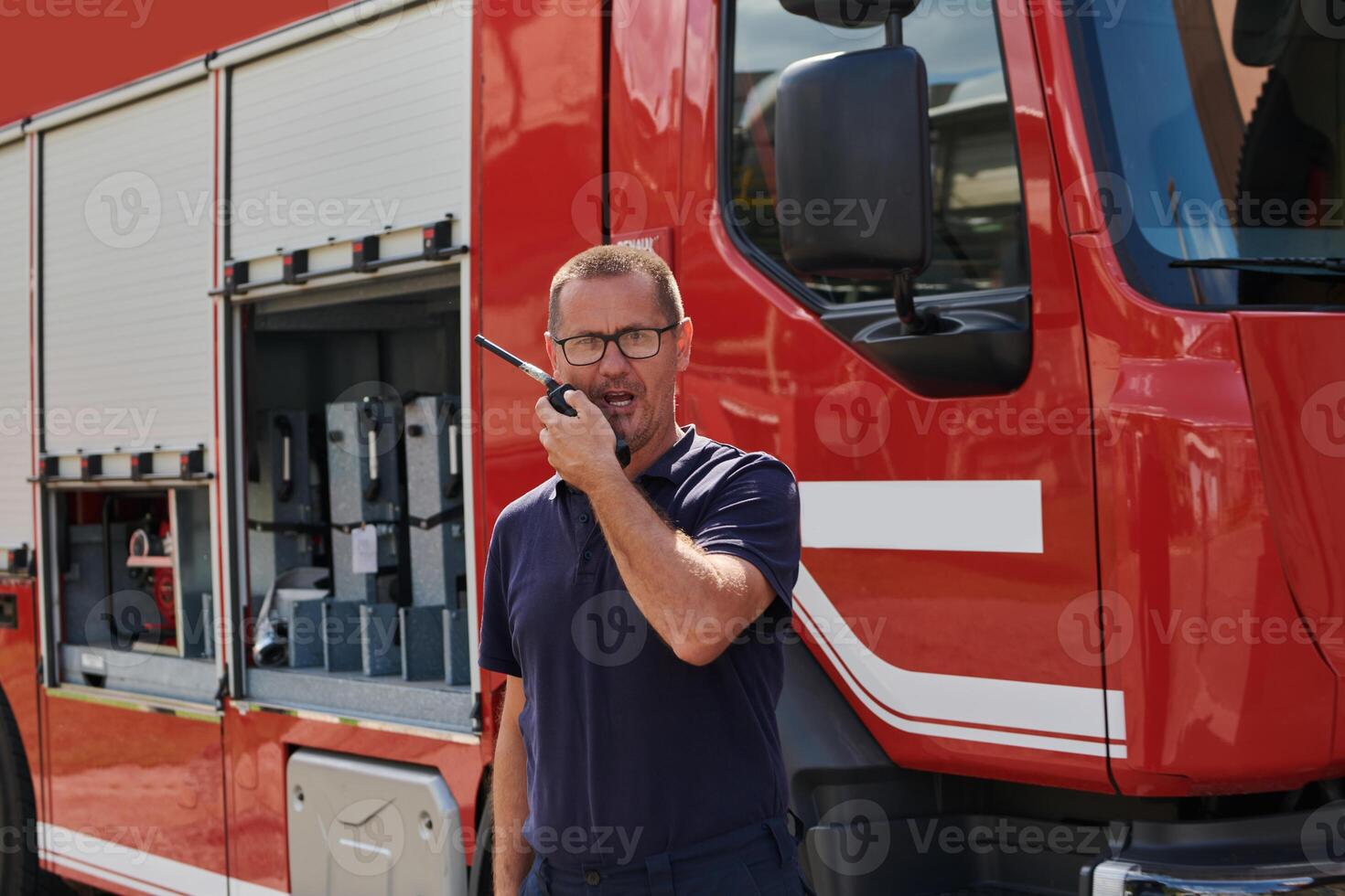 A dedicated firefighter, captured in a moment of communication, stands before a modern firetruck, showcasing the seamless integration of technology in emergency response photo