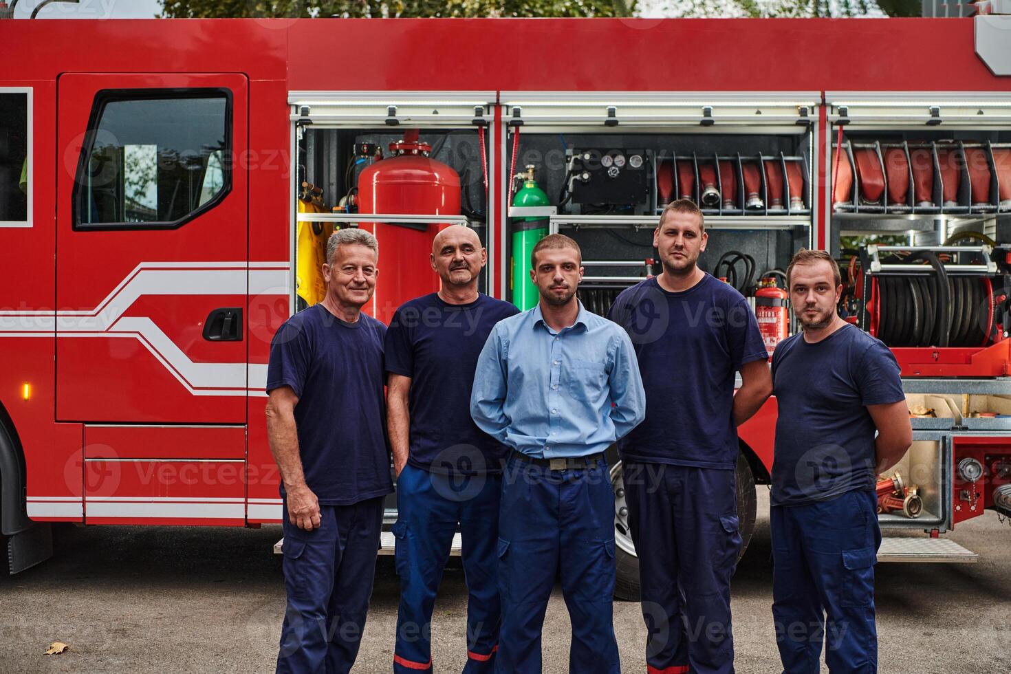 A skilled and dedicated professional firefighting team proudly poses in front of their state of the art firetruck, showcasing their modern equipment and commitment to ensuring public safety. photo
